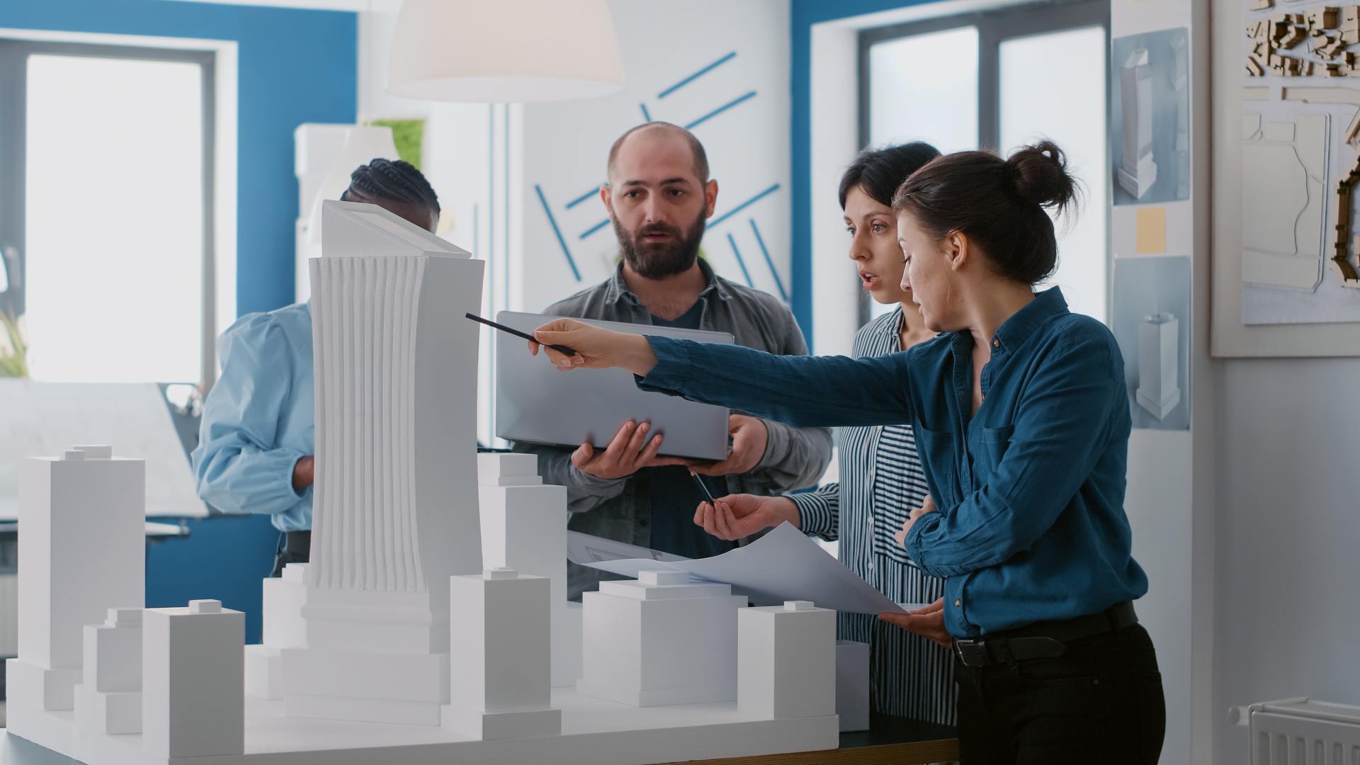 multi-ethnic-people-working-with-laptop-tablet-building-model-architecture-project-coworkers-doing-teamwork-design-maquette-construction-layout-with-blueprints (1)